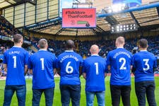 Former Chelsea players Gary Cahill, Jimmy Floyd Hasselbaink and Eiður Guðjohnsen (named shirts) and Chelsea fans (l-r) Marcus Cuthbert, Carlo Capelli, and Fabio Agostini show the Samaritans’ 24-hour helpline number 116 123 printed on the back of their shirts during the launch of the TalkMoreThanFootball campaign from Three, sponsors of Samaritans, during halftime of Chelsea vs Brighton at Stamford Bridge. Picture date: Saturday 15 April, 2023. PA Photo. The campaign aims to encourage fans to open up after new research reveals that British people are twice as likely to talk about football than their mental wellbeing. Picture credit should read: Matt Crossick/PA Wire.