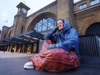 *** FREE FOR EDITORIAL USE *** Crisis CEO Matt Downie MBE with ambassadors and award winning actors Imelda Staunton and Jonathan Pryce unveils a giant, hyper-real sculpture of a person experiencing homelessness at London King’s Cross station, with the powerful protest coming after new research revealed 300,000 households could be left homeless next year