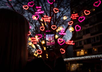 EDITORIAL USE ONLY Love actually is in Connaught Village. People gathered to see the festive lights in Connaught Village and to see the Tree of Love, Joy and Hope receive a yuletide makeover displaying quotes from the festive film, Love Actually; 'to me you are perfect, first lobster, all I want for Christmas is you, and I feel it in my fingers'. Writer and Director, Richard Curtis CBE said “One of my favourite bits of Love Actually is all the shots of the beautiful London Christmas lights - it’s a lovely surprise now, years later, to have Love Actually itself as part of the lights.”