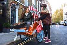 EDITORIAL USE ONLY Christy Bucklow on the Merchant Gourmet ‘Chestnut Chariot’, a rickshaw offering free rides to Christmas shoppers around central London to mark the expansion of the brand’s chestnut snack range. Issue date: Thursday November 24, 2022. PA Photo. The launch of the service, which offers riders a chestnut blanket to keep warm, chestnut snacks and chestnut-themed Christmas tunes, follows research showing that over a quarter of British people have never tried the historic festive snack.